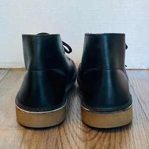 May include: A white ceramic mug with a black handle and the text "But First, Coffee" in a black, bold font. The mug is on a white surface. The mug is approximately 4 inches tall.