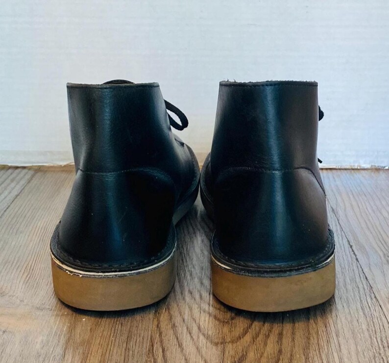 May include: A white ceramic mug with a black handle and the text "But First, Coffee" in a black, bold font. The mug is on a white surface. The mug is approximately 4 inches tall.