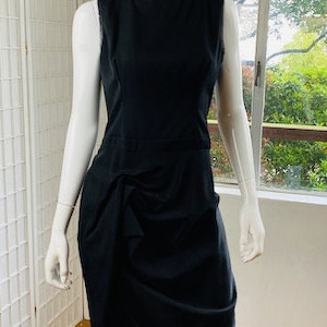 May include: A black sleeveless dress with a gathered skirt. The dress is fitted through the bodice and has a scoop neckline.