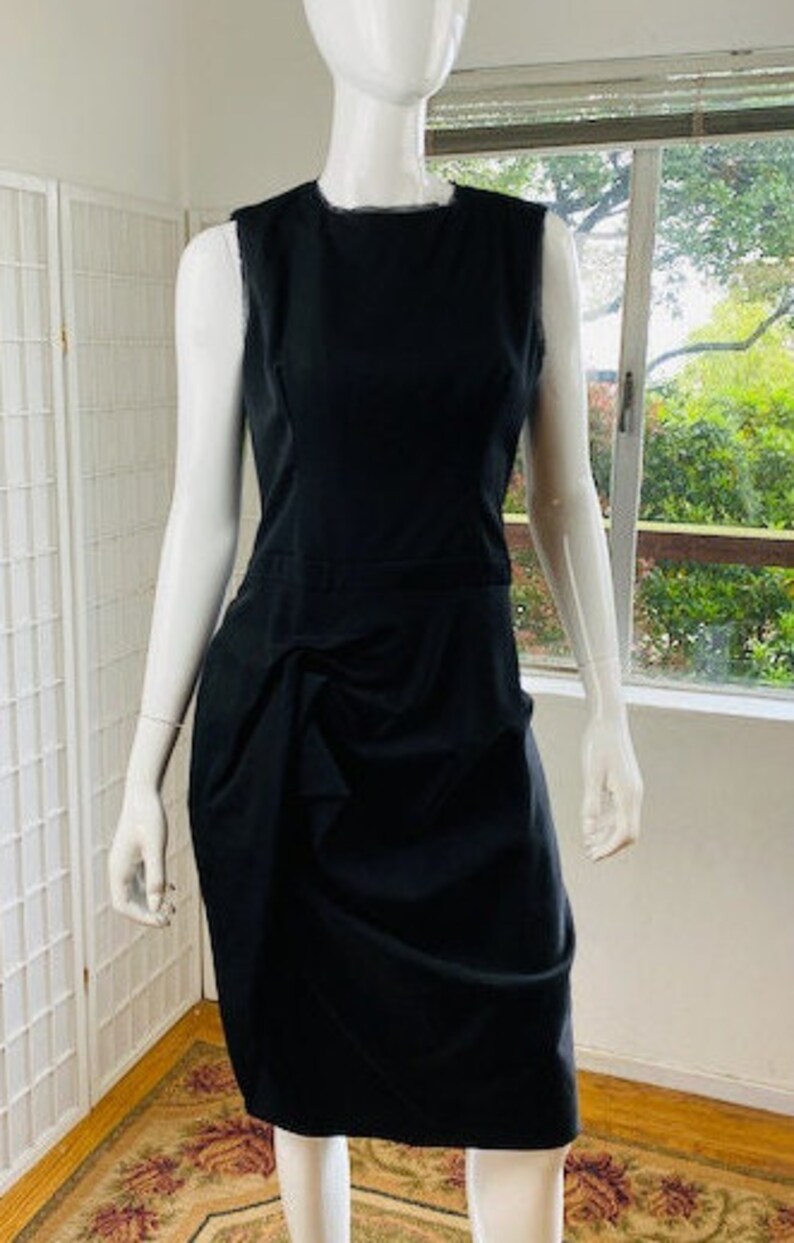 May include: A black sleeveless dress with a gathered skirt. The dress is fitted through the bodice and has a scoop neckline.