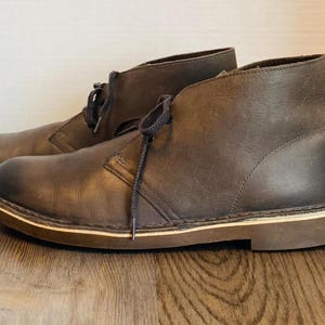 May include: A pair of brown leather ankle boots with laces. The boots have a cream-colored sole.