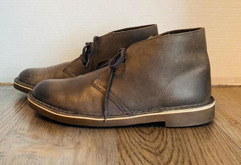 May include: A pair of brown leather ankle boots with laces. The boots have a cream-colored sole.