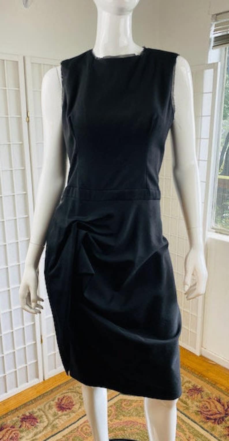 May include: A black sleeveless dress with a gathered skirt. The dress is fitted through the bodice and has a simple, rounded neckline.