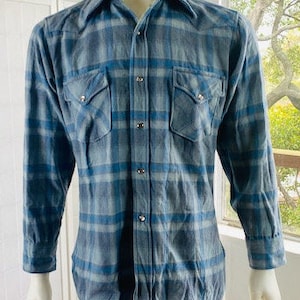 May include: A blue and white plaid flannel shirt with a button-down front and two chest pockets.
