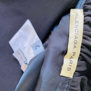 Może przedstawiać: Czarna sp&oacute;dnica plisowana z białą metką z napisem "2H" i złotą metką z napisem "BALENCIAGA. PARIS".