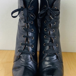 May include: Black leather ankle boots with lace-up closures. The boots have a chunky heel and a rounded toe.