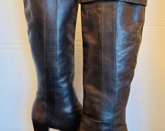May include: A pair of brown leather knee-high boots with a block heel. The boots have a fold-over cuff at the top.