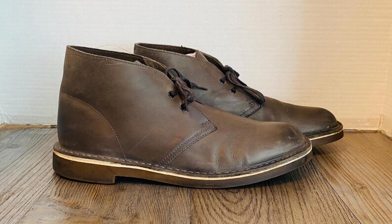 May include: A pair of brown leather ankle boots with laces. The boots have a cream-colored sole.