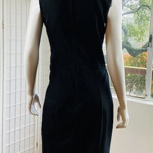 May include: A sleeveless black dress with a simple, fitted silhouette. The dress has a round neckline and a zipper closure in the back.