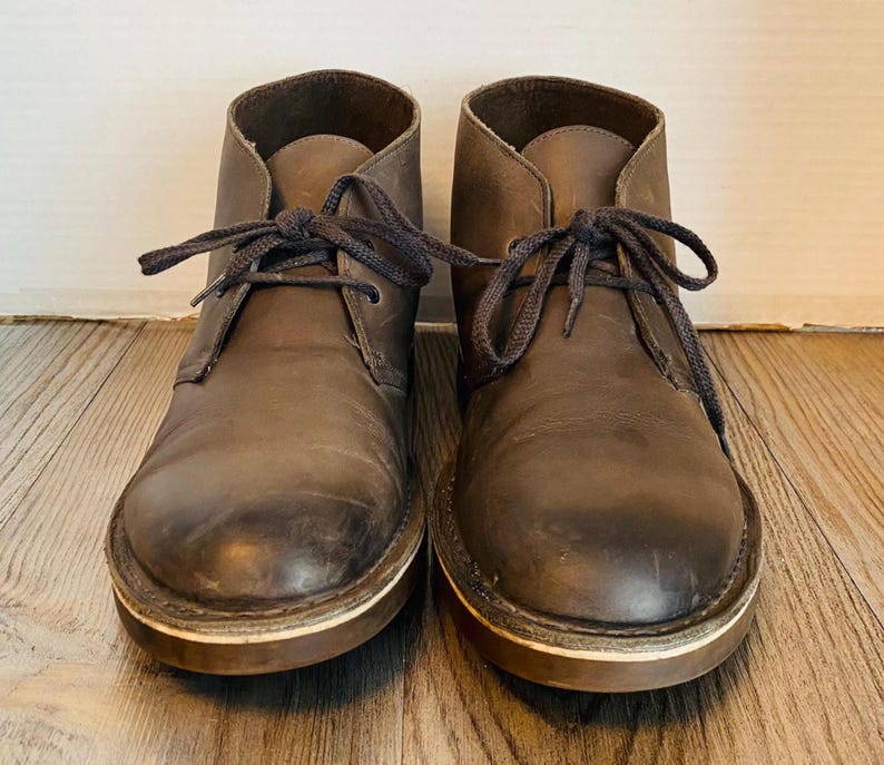 May include: A pair of brown leather ankle boots with laces. The boots have a worn look and are tied with dark brown laces.