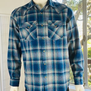 May include: A blue and white plaid flannel shirt with long sleeves and a button-up front.