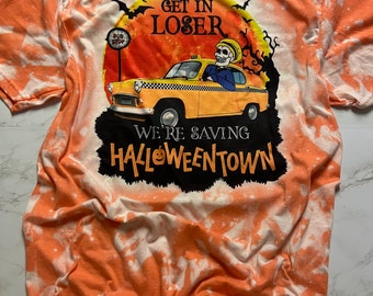 May include: Orange tie-dye t-shirt with a black and white graphic of a skeleton driving a yellow taxi cab. The graphic says "Get in Loser, We're Saving Halloweentown".