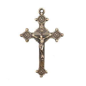 May include: A detailed silver-toned crucifix with a figure of Jesus Christ. The cross features ornate detailing, including decorative circular elements at the ends of the arms and a loop at the top for hanging. The figure of Christ is centrally positioned.