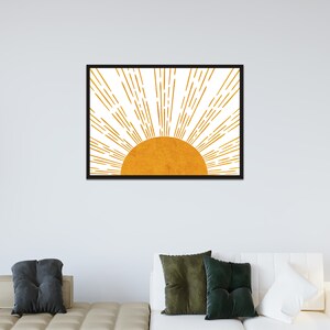 Puede incluir: Una impresi&oacute;n enmarcada de un sol estilizado con rayos naranjas sobre un fondo blanco.