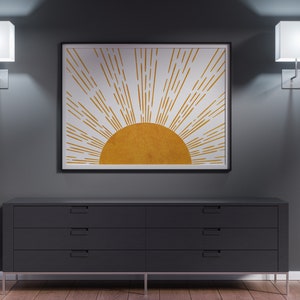 Puede incluir: Una c&oacute;moda negra con cuatro cajones y tiradores plateados se encuentra frente a una pared gris. Dos apliques de pared cuadrados blancos con bombillas iluminan la habitaci&oacute;n. Una impresi&oacute;n enmarcada de un sol estilizado con rayos dorados cuelga sobre la c&oacute;moda.