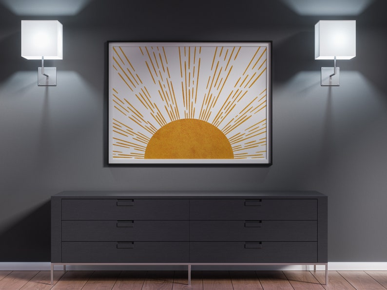 Puede incluir: Una c&oacute;moda negra con cuatro cajones y tiradores plateados se encuentra frente a una pared gris. Dos apliques de pared cuadrados blancos con bombillas iluminan la habitaci&oacute;n. Una impresi&oacute;n enmarcada de un sol estilizado con rayos dorados cuelga sobre la c&oacute;moda.