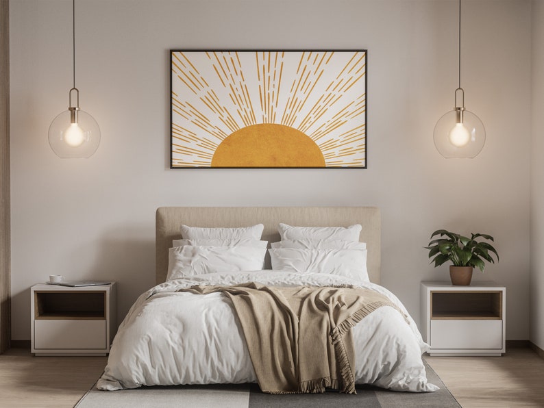 Puede incluir: Un dormitorio con una cama blanca, una manta marr&oacute;n y dos mesitas de noche. Las paredes son blancas y hay una impresi&oacute;n enmarcada de un sol amarillo con rayos blancos sobre la cama.