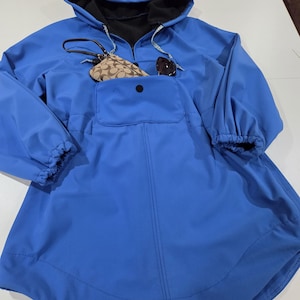 May include: A bright blue hooded poncho-style jacket with a large front pocket and drawstring hood. The jacket has long sleeves with elastic cuffs. A small purse and sunglasses are in the front pocket. The interior of the hood is black.