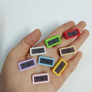 May include: Eight miniature digital clocks in various colors, including red, green, yellow, blue, white, and pink. Each clock displays the time "17:30".