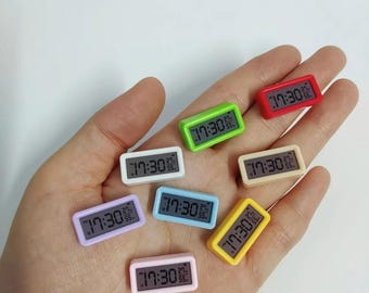 May include: Eight miniature digital clocks in various colors, including red, green, yellow, blue, white, and pink. Each clock displays the time "17:30".
