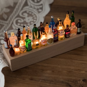 May include: A wooden shelf with miniature glass bottles of various colours and shapes, each with a different label. The bottles are lit from within, creating a warm glow.