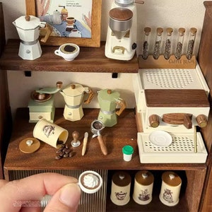 Peut inclure: Un ensemble de jeu miniature de café avec un moulin à café, une machine à expresso, des cafetières et des grains de café. L'ensemble comprend également une petite tasse de café avec de la crème fouettée.