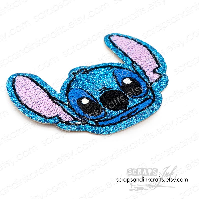 Puede incluir: Un parche bordado azul brillante con el personaje Stitch de Lilo & Stitch. El parche tiene colores azul claro, azul oscuro, negro y lavanda. El nombre de la tienda Etsy "scrapsandinkcrafts.etsy.com" es visible.