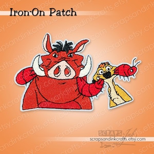May include: Embroidered iron-on patch featuring Pumbaa and Timon from The Lion King. Pumbaa is red with white tusks, and Timon is yellow with a red insect. The patch has the text "Iron-On Patch" at the top.
