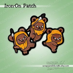 Pode incluir: Patch de passar a ferro com três Ewoks de desenho animado. Os patches são castanhos com pelo castanho claro e contornos pretos. Dois Ewoks seguram lanças. O texto "Iron-On Patch" está no topo. O URL da loja Etsy está na parte inferior.