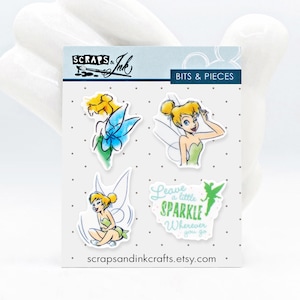 May include: Four colorful stickers featuring Tinkerbell from Disney's Peter Pan. The stickers include Tinkerbell in different poses, including flying, sitting, and with a sparkle effect. The text on one sticker reads "Leave a little sparkle wherever you go."
