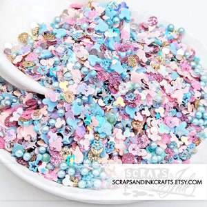 May include: A mix of blue, pink, and gold glitter, iridescent sequins, and pearl beads in the shape of stars, Mickey Mouse heads, and other shapes.