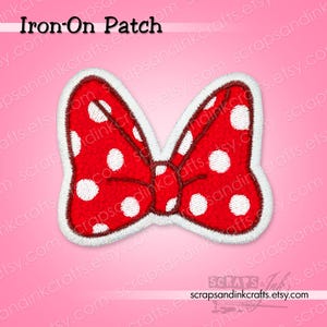 May include: Embroidered red bow with white polka dots and a white border. The text "Iron-On Patch" is above the bow. The bow is a decorative item, likely for clothing or accessories.