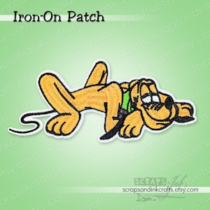 May include: An embroidered iron-on patch featuring a cartoon dog in a relaxed pose. The dog is primarily yellow with black accents, a green collar, and white outlines. The patch has the text "Iron-On Patch" at the top.