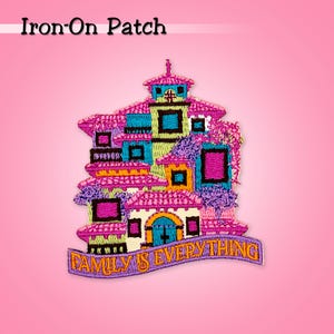 Könnte beinhalten: Aufbügler mit gesticktem, farbenfrohem Gebäudedesign mit rosa, blauen, grünen und gelben Akzenten. Der Aufnäher enthält den Text "FAMILY IS EVERYTHING" auf einem lila Banner. Ideal zum Dekorieren von Kleidung oder Accessoires.