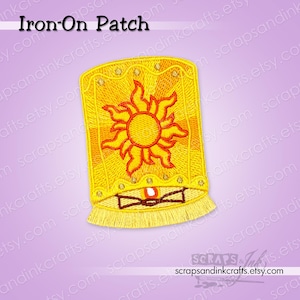May include: An embroidered iron-on patch featuring a yellow lantern design with a central orange sun motif. The lantern has a scalloped top edge with small gold dots, a fringed bottom edge, and a small flame visible at the base. Text reads Iron-On Patch.