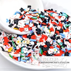 Pode incluir: Uma tigela branca cheia de granulados de argila polimérica coloridos. Os granulados têm a forma de cartas de jogar, corações, paus, espadas, ouros e flores. Os granulados são perfeitos para decorar bolos, cupcakes, biscoitos e outras sobremesas.