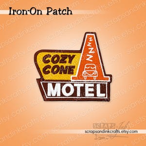 May include: An embroidered iron-on patch featuring a brown, yellow, and orange design. The patch displays the text COZY CONE MOTEL with a graphic of a traffic cone topped with ZZZ symbols and a sleeping car icon, all outlined in dark brown.