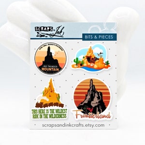 May include: Four colourful stickers featuring illustrations of Big Thunder Mountain Railroad, a popular ride at a theme park. The stickers include the ride's name, "The Thrill Seeker's Railroad", "Big Thunder Mountain", "This here is the wildest ride in the wilderness", and "Frontierland".