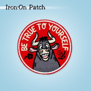 Pode incluir: Remendo redondo para passar a ferro com fundo vermelho e borda branca. O remendo apresenta um touro sorridente com o texto "BE TRUE TO YOURSELF" em branco. Elementos florais decorativos nas laterais. O texto "Iron-On Patch" está no topo.