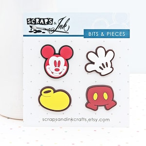 May include: A set of four colourful Mickey Mouse-themed embellishments. Includes a red Mickey Mouse head, a white glove, a yellow shoe, and red shorts with yellow buttons. The card reads "BITS & PIECES" and "scrapsandinkcrafts.etsy.com".