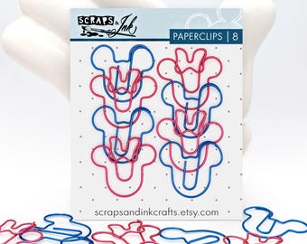May include: A pack of eight paperclips in the shape of a cartoon mouse head, in red and blue wire. The package reads "PAPERCLIPS | 8" and "scrapsandinkcrafts.etsy.com". Some paperclips are scattered below the package.