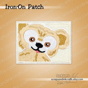 May include: Embroidered iron-on patch featuring a cartoon bear with tan fur, white eyes, and a black nose and mouth. The patch is rectangular with a white border and the text "Iron-On Patch" at the top. The Etsy shop URL is visible at the bottom.