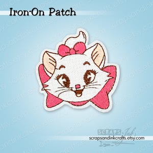 Pode incluir: Um patch bordado para passar a ferro com um gato branco com detalhes e laço rosa. O patch tem o texto "Iron-On Patch" no topo. O gato tem olhos castanhos e um laço rosa. Um acessório decorativo.