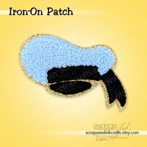 May include: An iron-on patch in the shape of a coffee pot, featuring a light blue top, black body, and gold glitter trim. The text "Iron-On Patch" is at the top. The Etsy shop name is at the bottom.