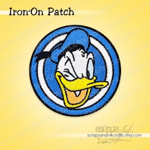 Peut inclure: Écusson thermocollant brodé représentant Donald Duck dans un cercle bleu et blanc. Le patch a un bec jaune, des yeux noirs et un chapeau bleu. Le texte "Iron-On Patch" est en haut.