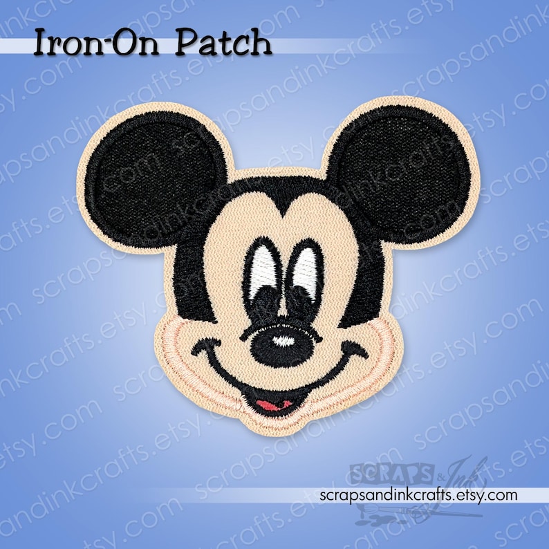 Pode incluir: Um patch bordado para passar a ferro com o rosto do Mickey Mouse. O patch tem um rosto bege, orelhas pretas e uma express&atilde;o sorridente com a boca vermelha. O texto "Iron-On Patch" est&aacute; no topo.
