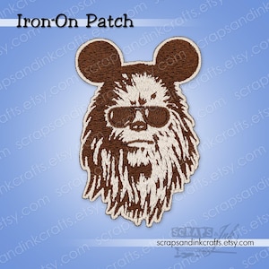 May include: An embroidered iron-on patch featuring a brown and white design of a furry character wearing sunglasses. The patch has the text "Iron-On Patch" at the top. The Etsy shop name "scrapsandinkcrafts.etsy.com" is at the bottom.