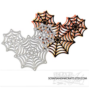 May include: Three metal die-cut spiderwebs in different sizes. The largest spiderweb is silver, the medium spiderweb is black, and the smallest spiderweb is orange. The spiderwebs are layered on top of each other.