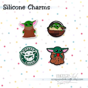 May include: Silicone charms featuring a green character with large ears in various poses. One charm shows the character in a brown robe, another in a pod, and a third holding a heart. A fourth charm has the text "Coffee I Need".