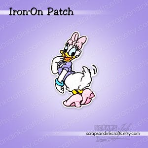 Peut inclure: Un écusson thermocollant représentant Daisy Duck dans une pose enjouée. L'écusson montre Daisy avec son haut violet, son nœud rose et ses chaussures, avec un corps blanc et un bec jaune. Le texte "Iron-On Patch" est en haut.
